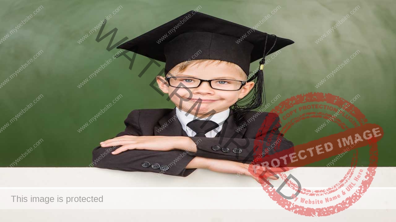 Happy boy in graduation hat looks out from behind a banner آموزش مقاله نویسی از پایان نامه